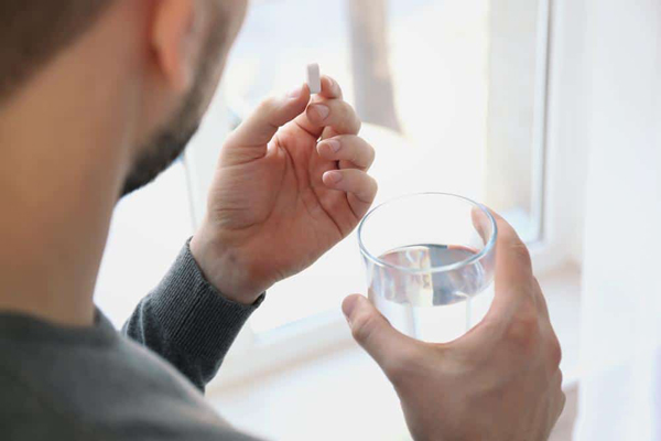 Por qué se nos cae mucho el pelo - Hombre tomando una pastilla de finasteride, la cual ayuda a detener la caída del cabello