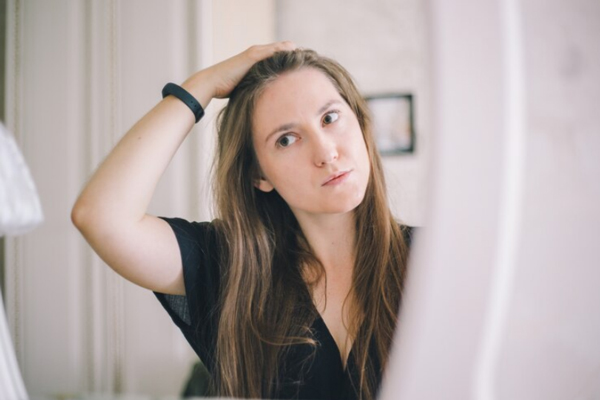 Mujer observando en el espejo la salud de su cabello liso, el cual conserva la hidratación por más tiempo gracias a su estructura