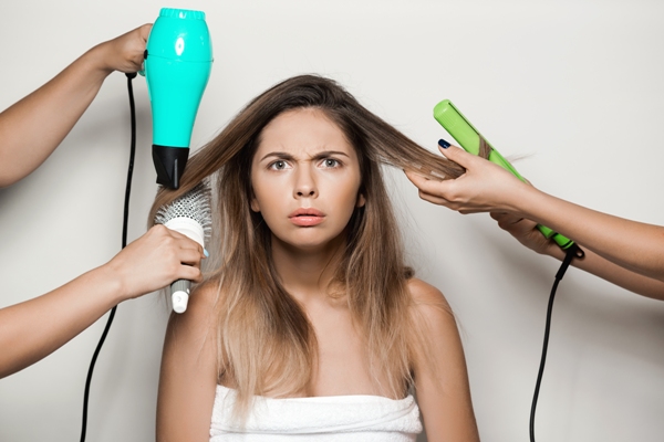 Mujer asombrada al conocer el daño que ocasiona en el cabello el uso de herramientas de calor, ya que contribuye a la deshidratación de las hebras capilares