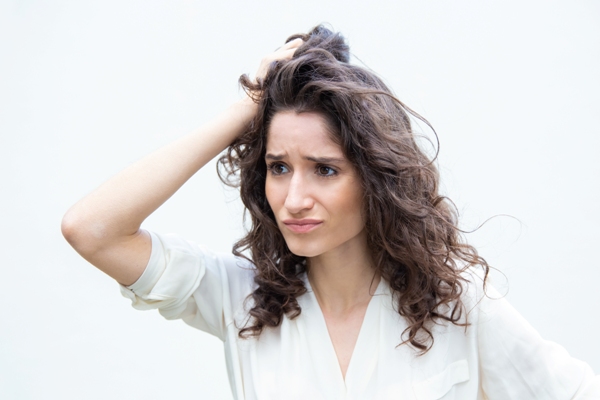 Mujer preocupada por el daño que está presentando su cabello, luego de utilizar químicos que deshidrataron las hebras capilares