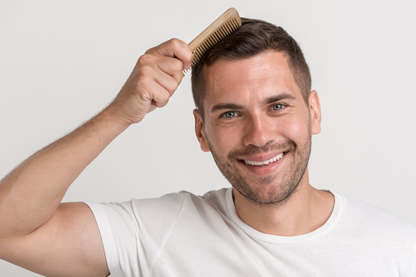 Hombre peinando su cabello luego del implante de pelo, el cual le ayudó a recuperarse de la alopecia