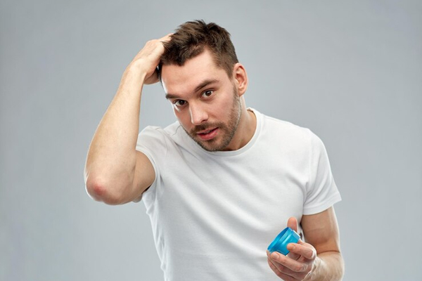 Trasplante capilar 3 meses después - Hombre aplicando un producto capilar para estimular el crecimiento del cabello implantado, siguiendo las recomendaciones del médico especialista