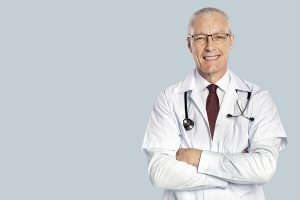 Cómo escoger un cirujano capilar - Doctor de dilatada experiencia sonríe y se cruza de brazos mientras espera a sus pacientes