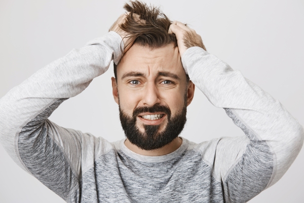 Alopecia nerviosa - hombre llevándose las manos a la cabeza con cara de estar estresado por algo