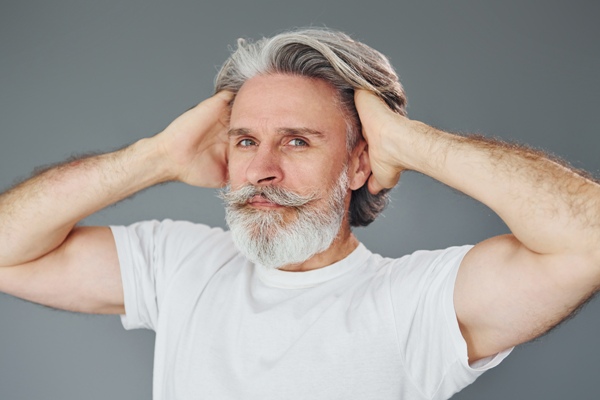 Canas - Adulto mayor con barba y mostacho introduce las manos en su cabellera para ratificar su volumen y abundancia 