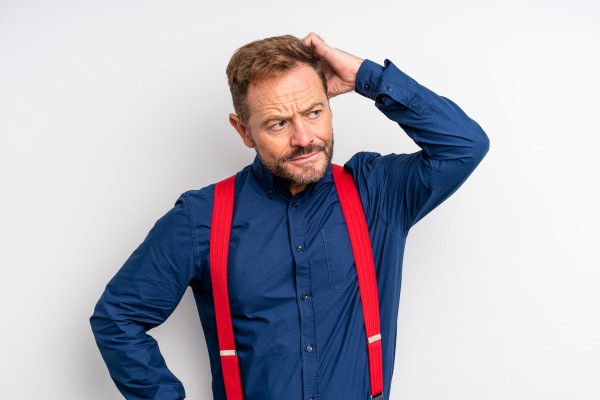 Pica la cabeza - hombre con camisa azul y tirantes rojos rascándose la cabeza