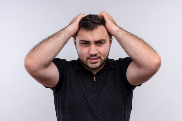 hombre sujetándose el cabello con las manos y con cara de estar estresado