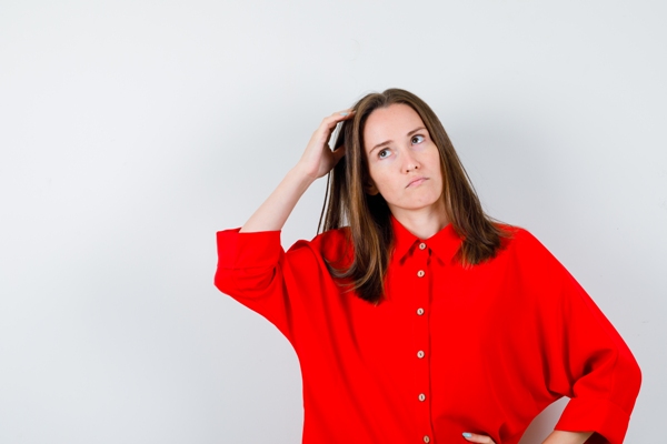 Lavarse el cabello todos los días - mujer con una camisa roja y cabello largo pasando su mano por la melena