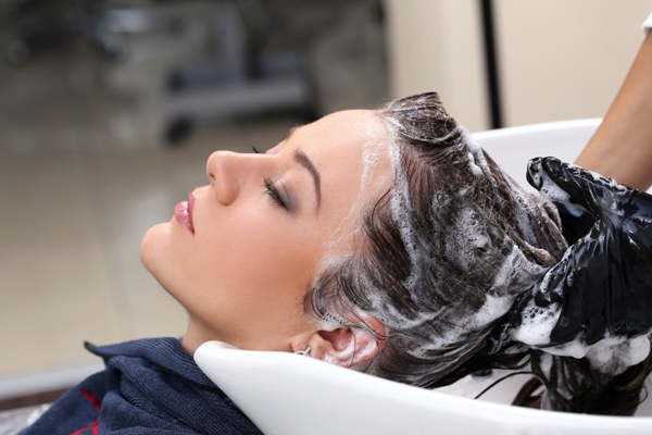 Pica la cabeza - mujer en la peluquería relajada mientras le lavan el cabello