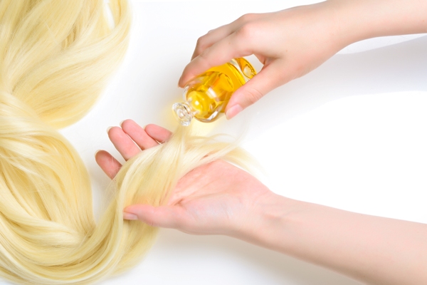 Beneficios del vinagre para el cabello - Joven aplica aceite natural en las puntas de una cabellera teñida para aumentar la hidratación y prevenir quiebres