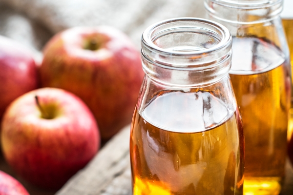 Beneficios del vinagre para el cabello - Vista ampliada de dos frascos de vidrio destapados con jugo fermentado de manzanas