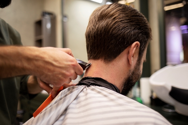 Cortes de pelo en el hombre - Barbero cortando el cabello de un hombre con una maquinilla eléctrica, para crear un estilo que lo haga ver más atractivo