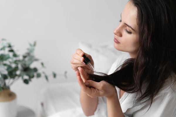 Aceite de coco en el pelo - mujer aplicando aceite de coco a las puntas de su cabello