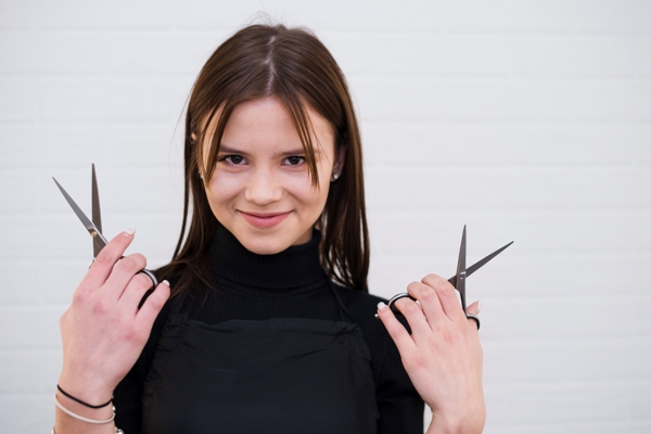 Corte de pelo en la mujer - Mujer sosteniendo un par de tijeras, las cuales sirven para realizar un corte de pelo adecuado según su rostro
