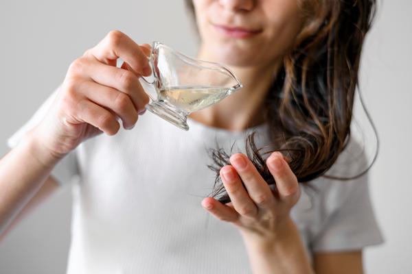 Aceite de coco en el pelo - mujer aplicando aceite de coco a las puntas de su cabello