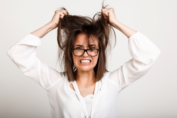 Mujer estresada debido a la picazón intensa que presenta en su cabello, a causa de un hongo que genera la descamación del cuero cabelludo