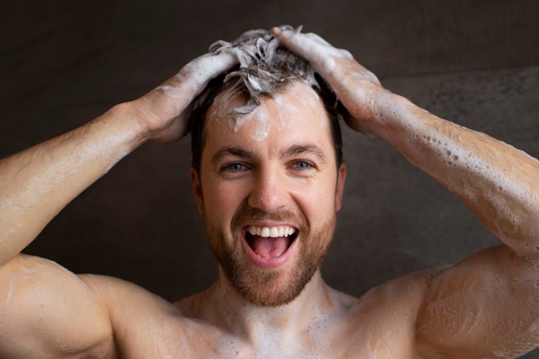 Cuántos pelos tenemos en la cabeza - Hombre lavando su cabello con un champú fortificante, el cual estimula el crecimiento capilar