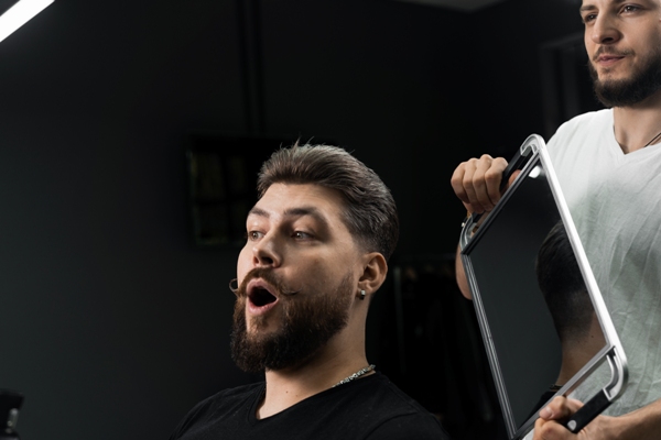Cortes de pelo en el hombre - Estilista mostrando los resultados a su cliente luego de cortarle el cabello acorde a los rasgos faciales, para hacerlo lucir más atractivo