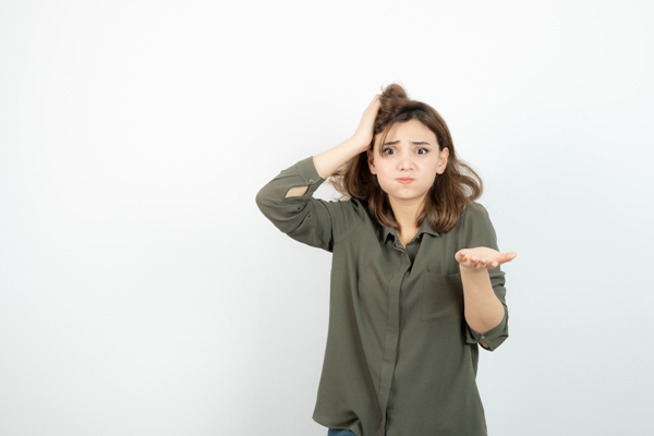 Duele el cabello - mujer con camisa verde y la mano en la cabeza preguntándose porque le duele la cabeza