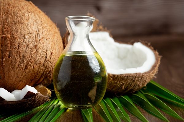 Aceite de coco en el pelo - coco entero con otro partido, una hoja del cocotero y un frasco con aceite de coco