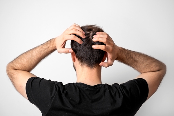 Hombre de espalda tocando su cabello, el cual se encuentra sano y abundante