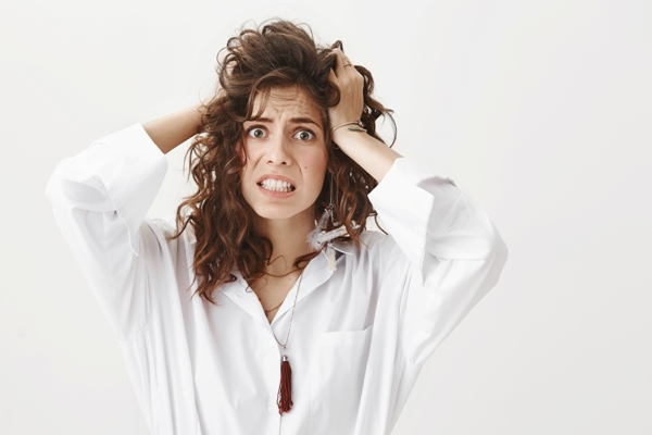 Duele el cabello - mujer agarrándose el cabello con muestras de estar sufriendo fuertes dolores