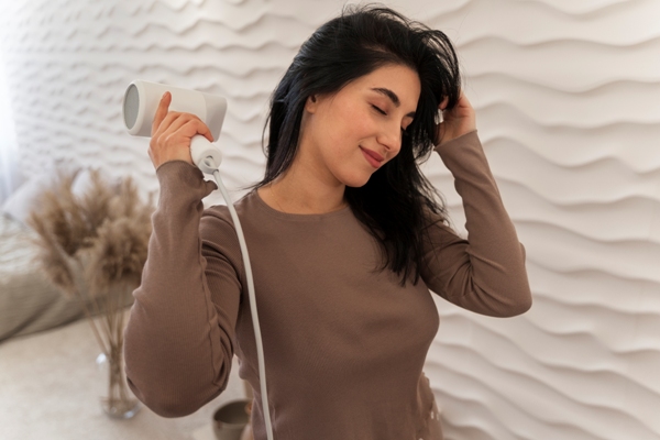 mujer en el dormitorio secándose el cabello con cara de felicidad