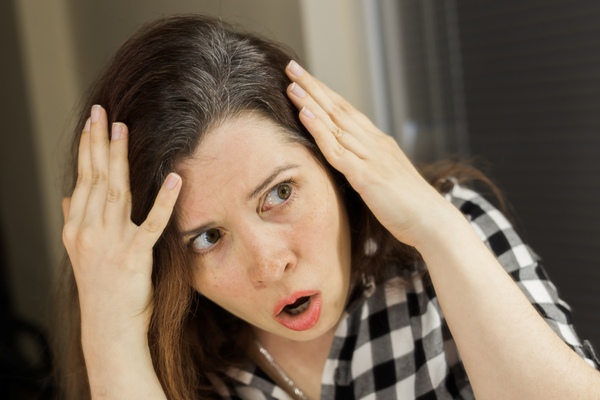 Causas de la caspa - Mujer abrumada por observar caspa en su cabello, como consecuencia de una mala higiene capilar