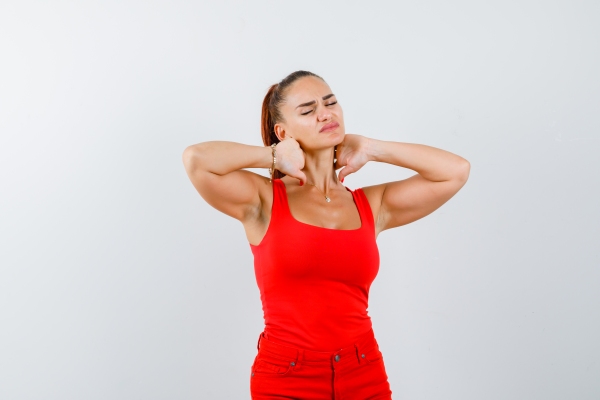 mujer vestida con un conjunto rojo llevándose las manos al cuello por el dolor