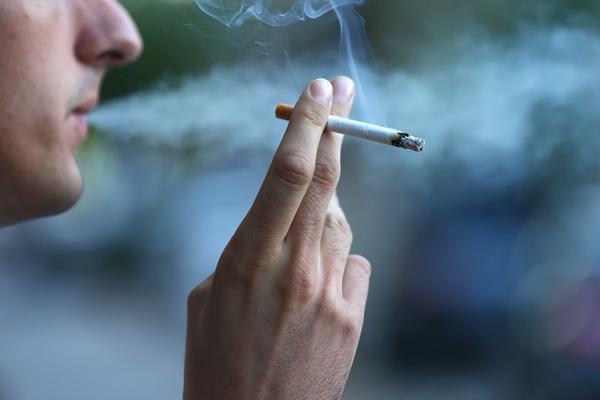 Fumar aumenta la caída del pelo - hombre fumándose un cigarrillo en la calle