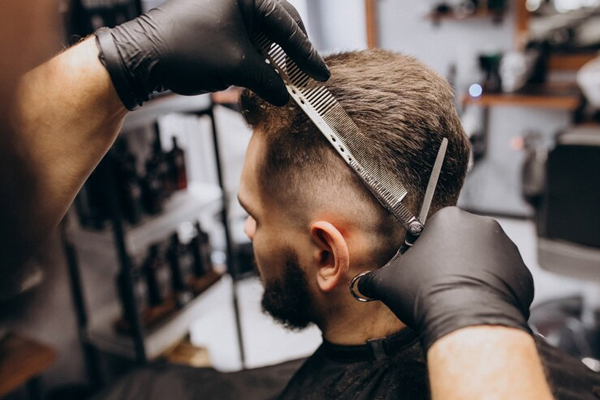 barbero cortando el cabello de un cliente masculino, para crear un nuevo look que resalte su estilo