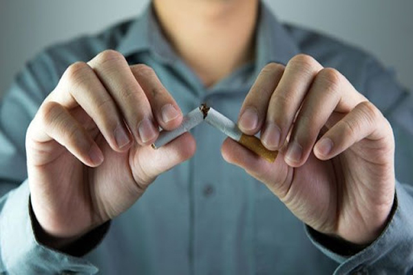 Fumar aumenta la caída del pelo - hombre rompiendo un cigarro que tiene entre sus manos