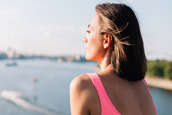 Cómo envejece nuestro pelo - Mujer mirando al horizonte con un cabello revitalizado y sin envejecimiento capilar gracias al cuidado adecuado