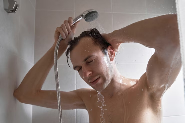 Cuidar el pelo en los hombres - Hombre lavando su cabello con un chorro de agua suave, para no dañar los folículos pilosos