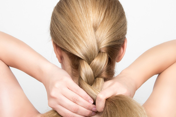 mujer rubia realizándose unas trenza bajas
