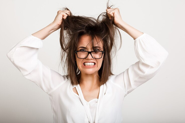 Salud mental - mujer con gafas estresada tarándose del cabello con violencia
