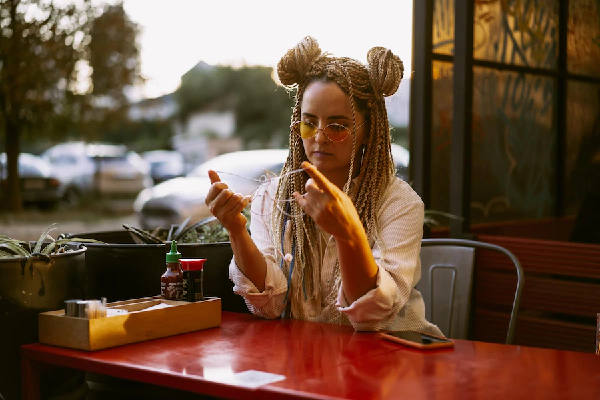 alopecia por tracción peinado con rastas - mujer sentada en un restaurante con el cabello lleno de trenzas y un recogido en cada lado