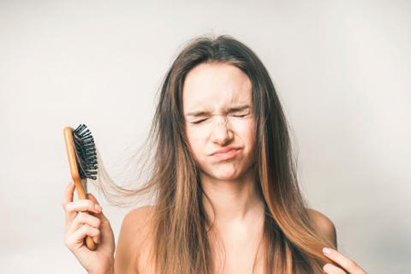 alopecia por tracción - mujer con cara de dolor al cepillar el cabello