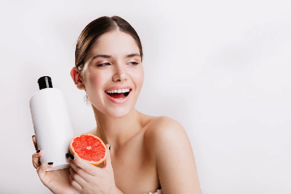 Champu para estimular el crecimiento del cabello - Mujer sostiene un producto capilar con esencia de toronja