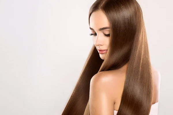 Keratina - Mujer de cabello castaño exhibe su larga y abundante melena de perfil 