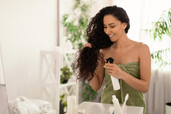 Agua de arroz para el pelo - Mujer de cabello rizado segmenta su pelo para aplicar un tónico capilar a base de ingredientes naturales