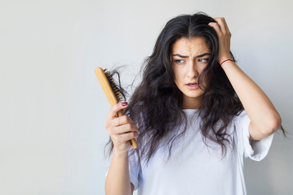Champús para estimular el crecimiento del cabello - Mujer de cabello negro se muestra preocupada ante una fase de efluvio telógeno