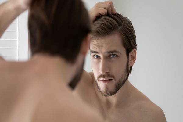 Champús para crecer el pelo - Hombre rubio evalúa la densidad de su melena frente al espejo