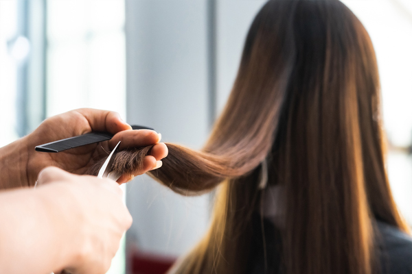 Cuidar el pelo en las mujeres - Estilista cortando las puntas del cabello de una mujer, para estimular el crecimiento capilar