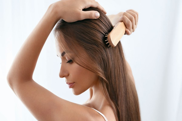 Keratina - Mujer sostiene su cabeza para mejorar el agarre mientras desenreda su cabello 