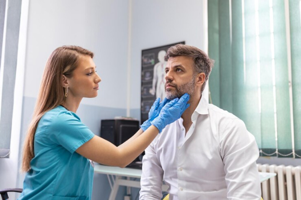 Champús para crecer el pelo - Endocrino examina el tamaño de la glándula de la tiroides de un paciente en consulta