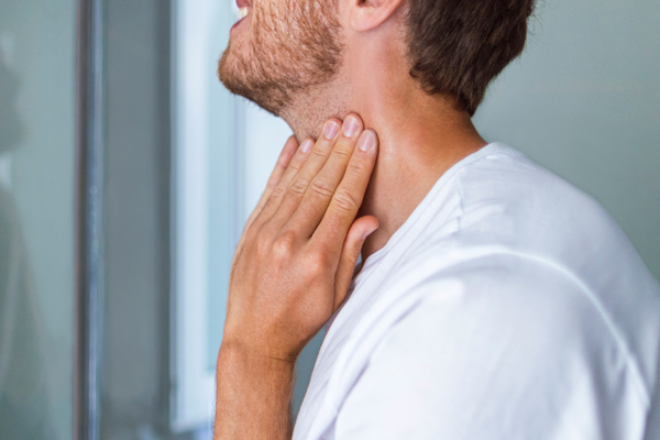 Champús para estimular el crecimiento del cabello - Hombre palpa su tiroides antes sospechas de anomalías hormonales en su organismo