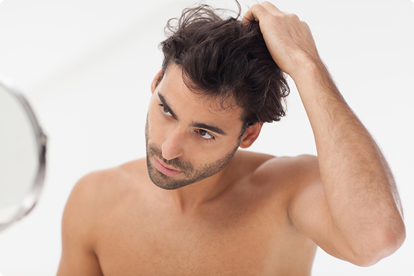 Hombre moreno peina su cabello con la mano tras cumplir con su rutina de cuidado capilar