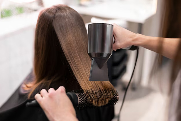 Keratina - Estilista sella tratamiento capilar alisante sobre el cabello de una cliente 