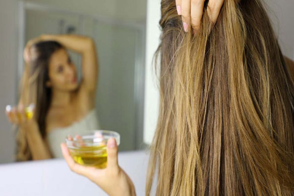 Aceite de oliva - Mujer de cabello largo y abundante aplica mascarilla capilar para aumentar el brillo y la hidratación de su pelo 